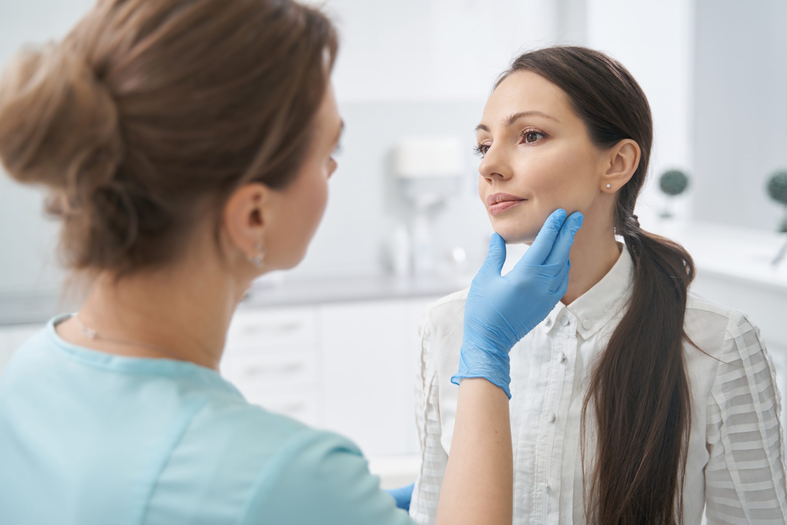 aesthetic therapist checking woman face skin in cosmetology clinic